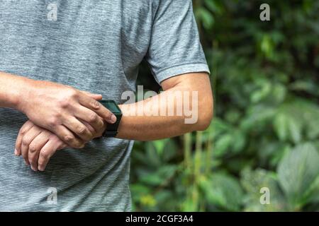 Fitness Tracker. Unriconoscable Man controllare i suoi progressi sportivi sullo smartwatch dopo l'allenamento all'aperto. Trail Runner in montagna Foto Stock