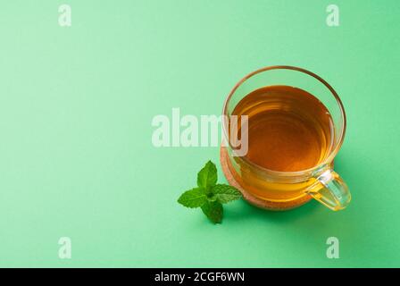 Tè alla menta e foglie di menta poste su sfondo verde con spazio per la copia Foto Stock