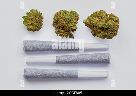 Tre Prerotoli di articolazioni di Cannabis con 3 fiori di cannabis essiccati sul lato. Foto Stock