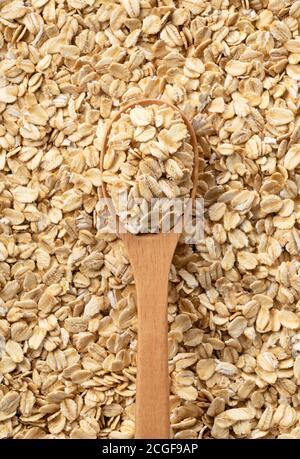 Una vista dall'alto di un cucchiaio di legno posto sulla parte superiore della farina d'avena posata su tutto lo schermo. Foto Stock
