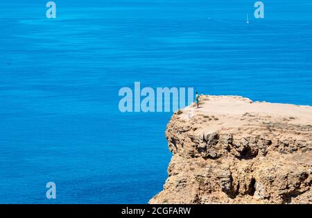 Un uomo sorge su un alto promontorio e guarda il mare. Foto di alta qualità Foto Stock