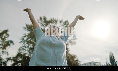 Donna anziana in pensione che gode della libertà di pensionamento. Mani distese nel parco, scatto a bassa angolazione. Foto di alta qualità Foto Stock