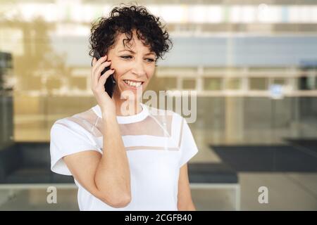 Un'imprenditore femminile sicuro e maturo che parla al telefono cellulare fuori dell'ufficio Foto Stock