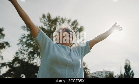 Donna anziana in pensione nel parco con mani allungate a basso angolo shot. Foto di alta qualità Foto Stock