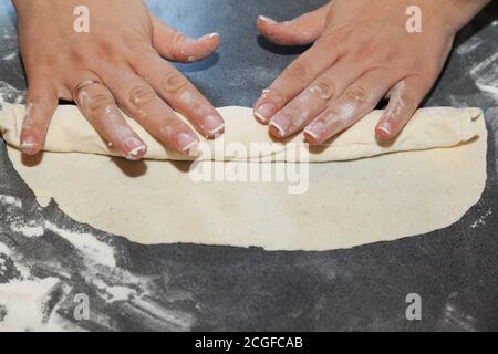 Mani che rotola l'impasto sottile con ripieno Foto Stock