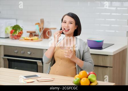 Donna incinta contiene vitamina la pillola e bicchiere di acqua sulla cucina della casa. Foto Stock