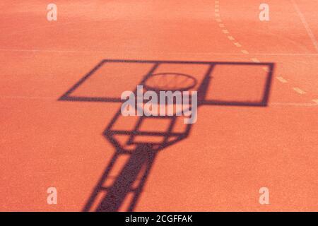 Ombra del rack con uno scudo e un anello da basket durante le giornate di sole all'aperto. Sfondo del gioco di basket Foto Stock