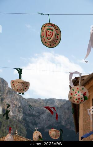 Divertenti cappelli decorati appesi da un filo sulla strada in un villaggio festival con le montagne sullo sfondo. Concetto di celebrazione Foto Stock