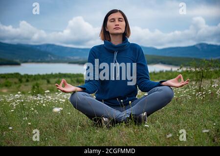 Una giovane donna che fa yoga sul campo. Sensibilità alla natura. Auto-analisi e ricerca dell'anima. Concetto spirituale ed emotivo. Foto Stock