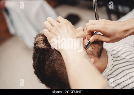 Barber processo di rasatura rasoio sopportato hipster uomo in barbiere Foto Stock