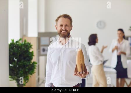 Felice proprietario sorridente di affari che guarda la macchina fotografica e tiene il legno razzo come simbolo della nuova start-up Foto Stock