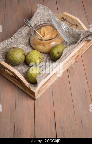 Vassoio di legno con un vasetto di purè di pere e pere fresche su sfondo chiaro . Orientamento verticale. Foto Stock