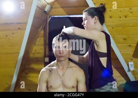 La moglie taglia i capelli sulla testa del marito a casa. Foto Stock