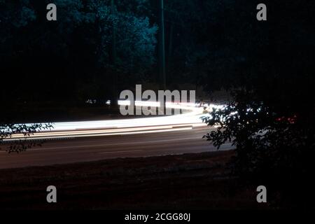 Auto bianco luci notturne luminose sulla banda autostradale su lunga esposizione. Luce a movimento rapido che illumina la città buia Foto Stock