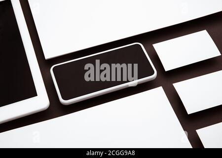 Dispositivo con schermo vuoto che oscilla sopra lo sfondo marrone. Telefono, tablet e schede. Stile ufficio, mockup moderno per la pubblicità. Spazio vuoto per il copyspace per il concetto di design, business e finanza. Foto Stock