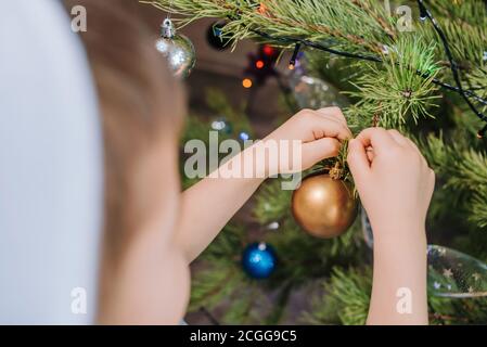 Festeggiamo il Natale. Carino capretto decorare l'albero di natale con i giocattoli di nuovo anno a casa Foto Stock