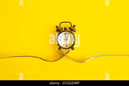 Orologio nero su sfondo giallo. Sveglia su due forcelle, trend Concept Time . Foto Stock