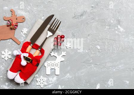 Vista superiore del nuovo anno utensili sul tovagliolo con decorazioni di vacanza e di renna su sfondo di cemento. Cena di Natale con il concetto di spazio di copia. Foto Stock