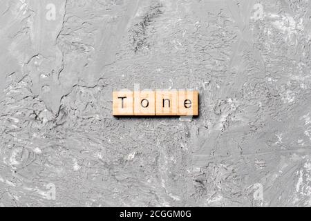 tono parola scritta su blocco di legno. tono testo su tabella di cemento per il vostro desing, concetto. Foto Stock