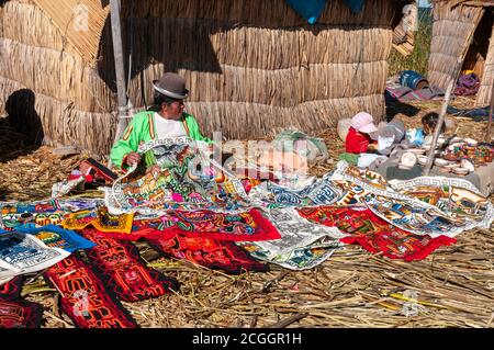 Una donna indigena che vende souvenir locali sulle isole galleggianti del lago Titicaca vicino Puno, Perù Foto Stock