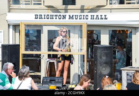 Brighton UK 11 settembre 2020 - UN sassofonista suona alcune melodie calde dietro uno schermo di plastica al bar Brighton Music Hall sul lungomare come la previsione è per il tempo caldo per spazzare attraverso la Gran Bretagna nel fine settimana e la prossima settimana: Credit Simon Dack / Alamy Live News Foto Stock
