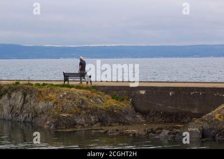 17 giugno 2020 UN uomo anziano solista cammina lungo il Muro di cemento che fa parte dell'antico Long Hole Porto nella contea di Bangor, in fondo all'Irlanda del Nord Foto Stock