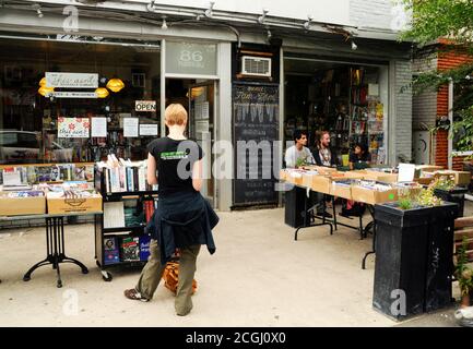 Una shopper donna cerca libri in vendita al di fuori di una libreria indipendente nel quartiere Kensington-Market del centro di Toronto, Ontario, Canada. Foto Stock