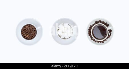 Set di tazze bianche con piattini con chicchi di caffè, caffè e cubetti di zucchero isolati su sfondo bianco, vista dall'alto. Foto Stock