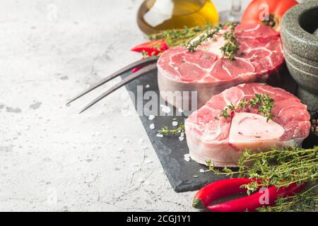 Freschi Stinco di vitello fette di carne di manzo per osso buco per la cottura sul tagliere con ingredienti e condimenti timo, pepe, sale. Foto Stock