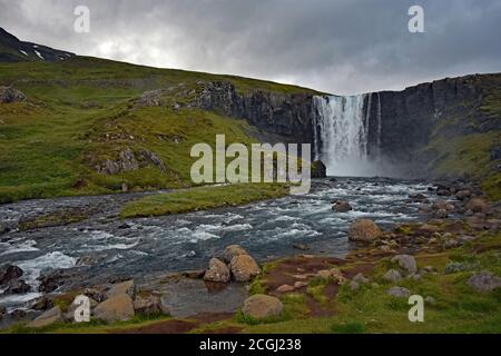 La cascata di Gufufoss scorre su una spettacolare scogliera a Seydisfjordur, Eastfjords, Islanda. L'acqua scorre lungo il fiume in un giorno cupo e coperto. Foto Stock