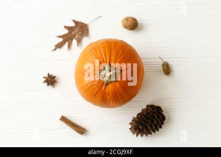 Posa piatta autunnale minimalistica. Zucca, foglia d'autunno, anice, cono di pino, acorno, noce e cannella bastone su sfondo bianco di legno. Felice Thanksgiv Foto Stock