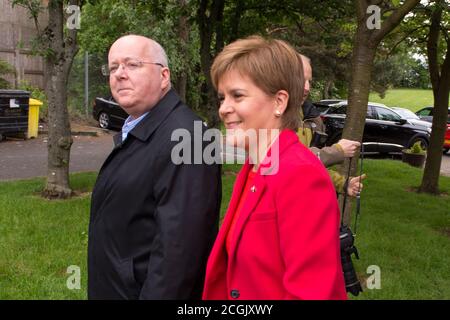 Uddingston, Scozia, Regno Unito. Nella foto: (A destra) Nicola Sturgeon - primo ministro della Scozia e leader del Partito nazionale scozzese (SNP), visto con il marito, (a sinistra) Peter Murrell CEO del Partito nazionale scozzese (SNP), Visita al suo seggio elettorale locale per esprimere il suo voto alle elezioni europee per la SNP per mantenere la Scozia in Europa. Credit: Colin Fisher/Alamy Live News. Foto Stock