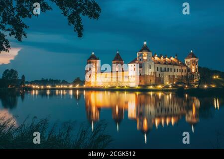 Mir, Bielorussia. Notte Vista panoramica del Castello di Mir In illuminazione serale con candelette di riflessioni sul lago di acqua. UNESCO Patrimonio dell'Umanità. Famoso punto di riferimento Foto Stock
