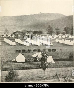 . La storia fotografica della Guerra civile : migliaia di scene fotografate 1861-65, con testo di molte autorità speciali . , RECENSIONE DELLE RECENSIONI CO. CAMBIARE LA GUARDIA ALLA PRIGIONE DI ELMIRA, 1864 questa foto dei quartieri delle guardie che hanno tenuto sotto controllo le migliaia di prigionieri confederati confinati a Elniira mostra che le condizioni erano molto migliori fuori dal campo che in. Le lunghe ombre delle linee regolari di tende indicano chiaramente che è stato preso nel tardo pomeriggio. Il fogliame sugli alberi fissa la stagione come estate. Gli uomini sono apparentemente impegnati in cambio di guardia. Dr. E. F. SA Foto Stock