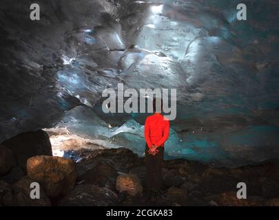 Uomo, adolescente si trova nella grotta di ghiaccio Alibek ghiacciaio in Dombay Foto Stock