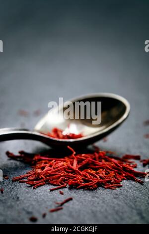 Lo zafferano in un cucchiaio su uno sfondo scuro, il fuoco selettivo, macro shot, profondità di campo Foto Stock