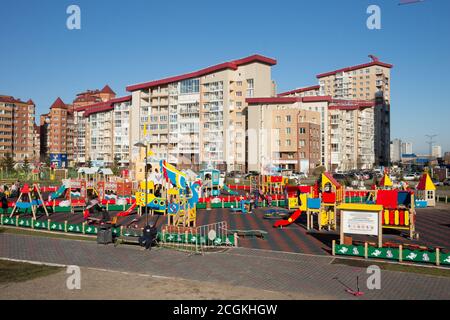 I bambini con i genitori giocano in un parco giochi pubblico in una zona residenziale di ​​Krasnoyarsk in una soleggiata giornata autunnale. Foto Stock