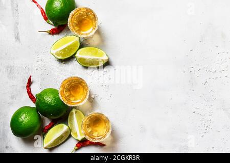 Tequila con lime, sale, peperoni rossi caldi su sfondo grigio, vista dall'alto Foto Stock