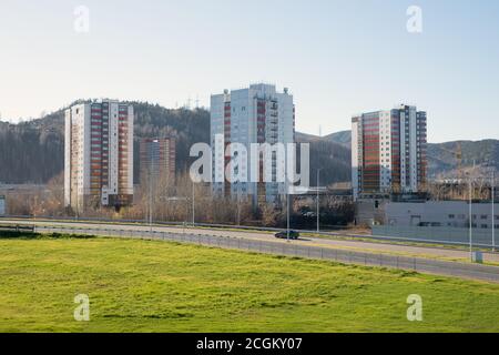 Area urbana con edifici residenziali e la strada sullo sfondo di una montagna boscosa, a Krasnoyarsk in autunno. Foto Stock