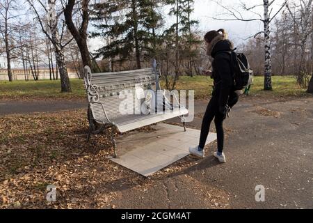 Girl fotografando una panchina commemorativa dedicata a tutti i musicisti rock defunti nel parco centrale della città di Krasnoyarsk in autunno. Foto Stock