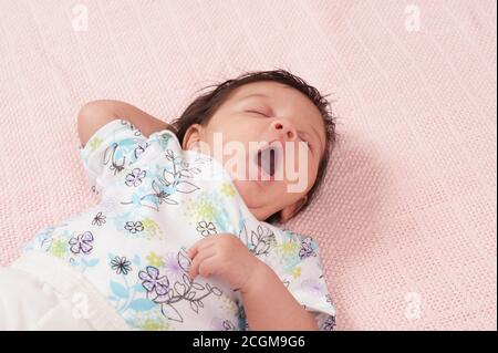 neonato bambino ragazza un mese di closeup sulla schiena reflex yawning, sonnolento Foto Stock