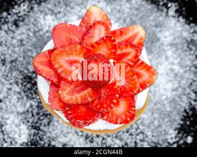 Deliziosa Pavlova con fragola in piatto nero e zucchero Foto Stock