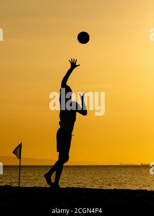 Sagome da Beach volley al tramonto giallo Foto Stock