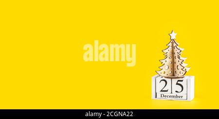 Albero di Natale minimalista su sfondo giallo pastello alla moda. Buono di auguri per buon Natale e Felice anno nuovo con spazio per la copia. Conce di vacanza invernale Foto Stock
