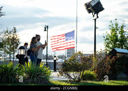 Bayonne, New Jersey, Stati Uniti. 11 settembre 2020: Una coppia legge e fotografa le informazioni sul monumento come una bandiera vola a metà albero al monumento lacrimale a Bayonne, New Jersey. Il Memoriale della goccia è stato un dono ufficiale del governo russo come memoriale alle vittime degli attacchi del settembre 11 nel 2001, 26 dei quali erano russi. Credito obbligatorio: Kostas Lymperopoulos/CSM credito: CAL Sport Media/Alamy Live News Foto Stock