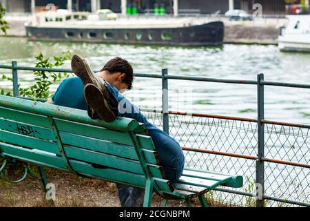 Parigi/Francia 06/13/2010: Un'immagine ravvicinata di un uomo seduto su una panchina con il suo amante sdraiato sul grembo la ragazza è fuori dalla cornice e vediamo solo Th Foto Stock
