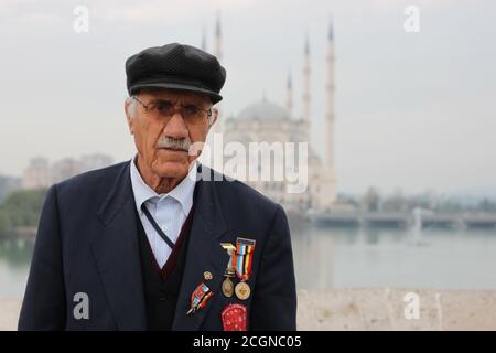 Adana, Turchia 12/26/2009: Ritratto di un anziano turco, veterano della guerra coreana, sullo storico ponte romano sul fiume Seyhan. Egli decora Foto Stock