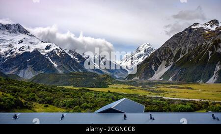 Vista sulle alte montagne sulla cima della montagna neve bianca in estate con cielo e nuvole con Erba verde in tutta l'area di Mount Cook Nat Foto Stock