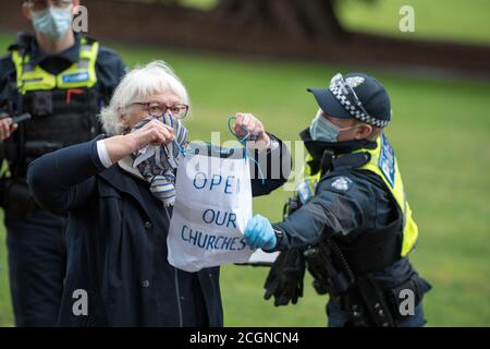 Melbourne, Australia 12 Set 2020, UN poliziotto stride un segno di protesta da una donna anziana protetista mani in Fitzroy Gardens che stava cercando di assistere a una protesta anti-maschera e anti-blocco nel parco di Melbourne Australia. Credit: Michael Currie/Alamy Live News Foto Stock