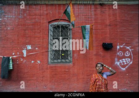 02.12.2011, Kolkata (Calcutta), Bengala Occidentale, India, Asia - UNA donna che indossa abiti tradizionali si trova di fronte a un edificio di mattoni rossi su una strada. Foto Stock